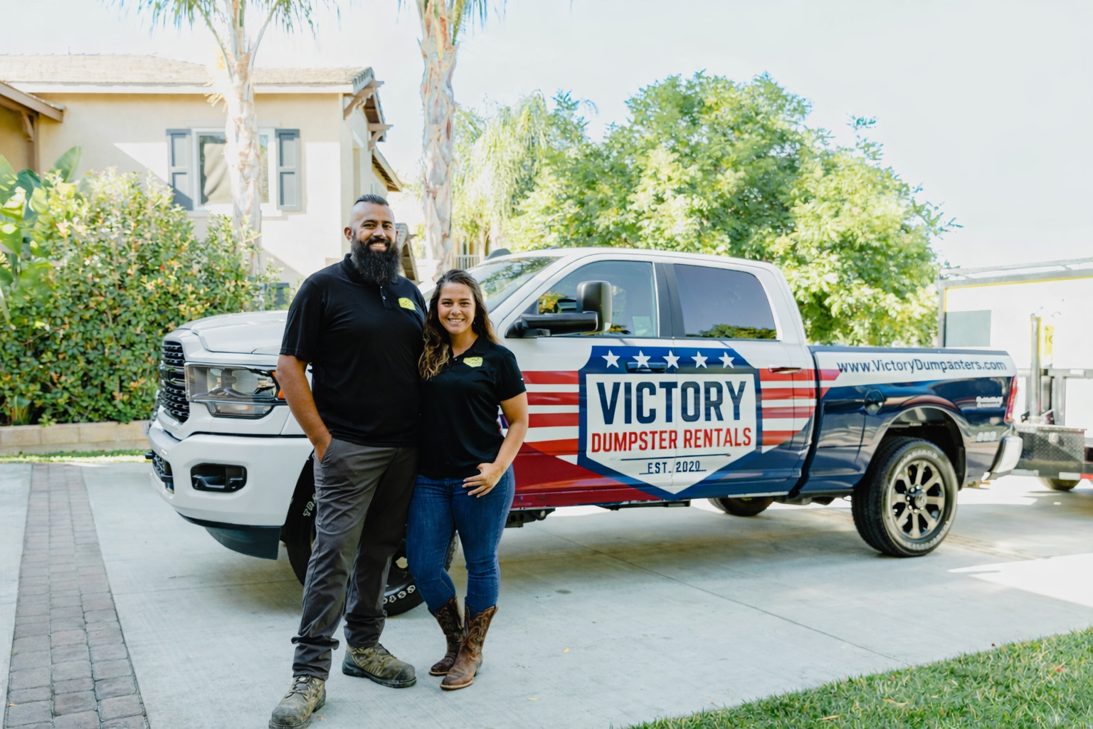 Abel and Tonya, owners of Victory Dumpster Rentals, standing in front of their branded truck in Murrieta, CA